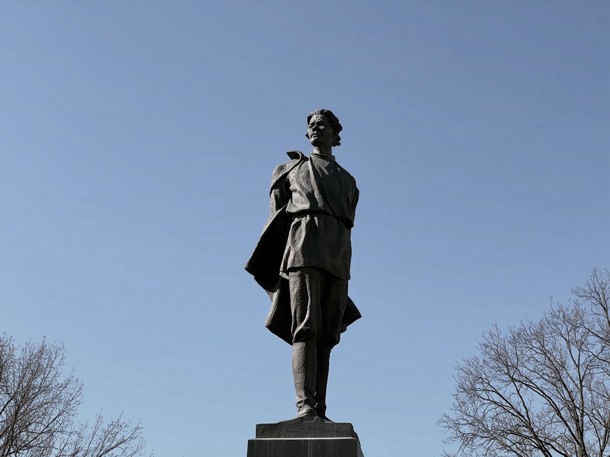 estatua de un hombre con chaqueta rusa sosteniendo un periódico